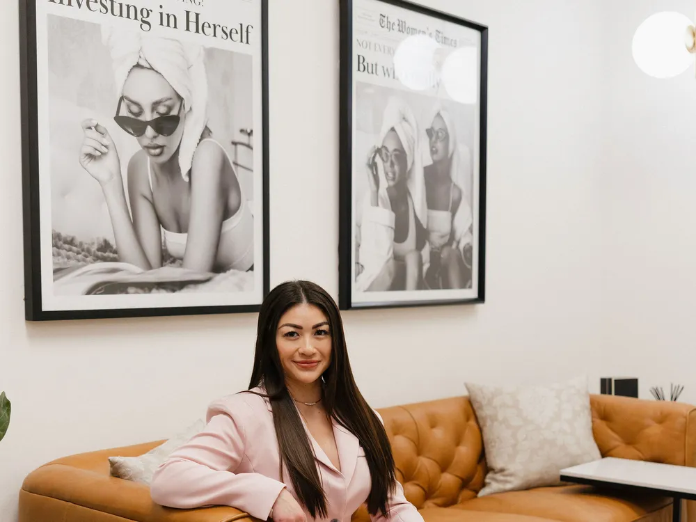 Leslie on the leather sofa in the Pink Diamond lounge beneath an Investing in Herself print