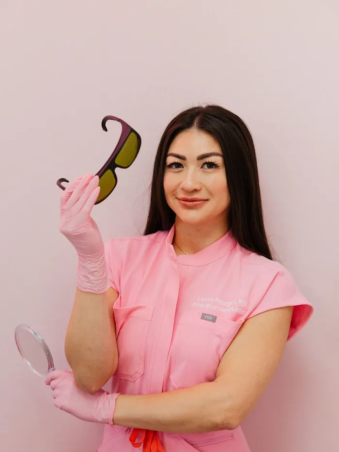 Leslie in scrubs holding laser safety goggles