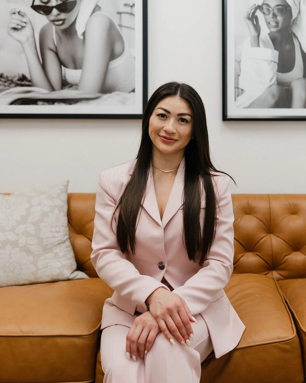 Leslie on the cognac leather sofa in the lobby, framed prints behind her