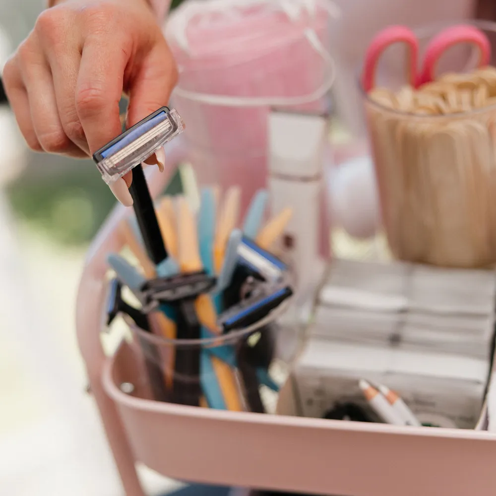 A hand lifting a razor from the pink prep caddy